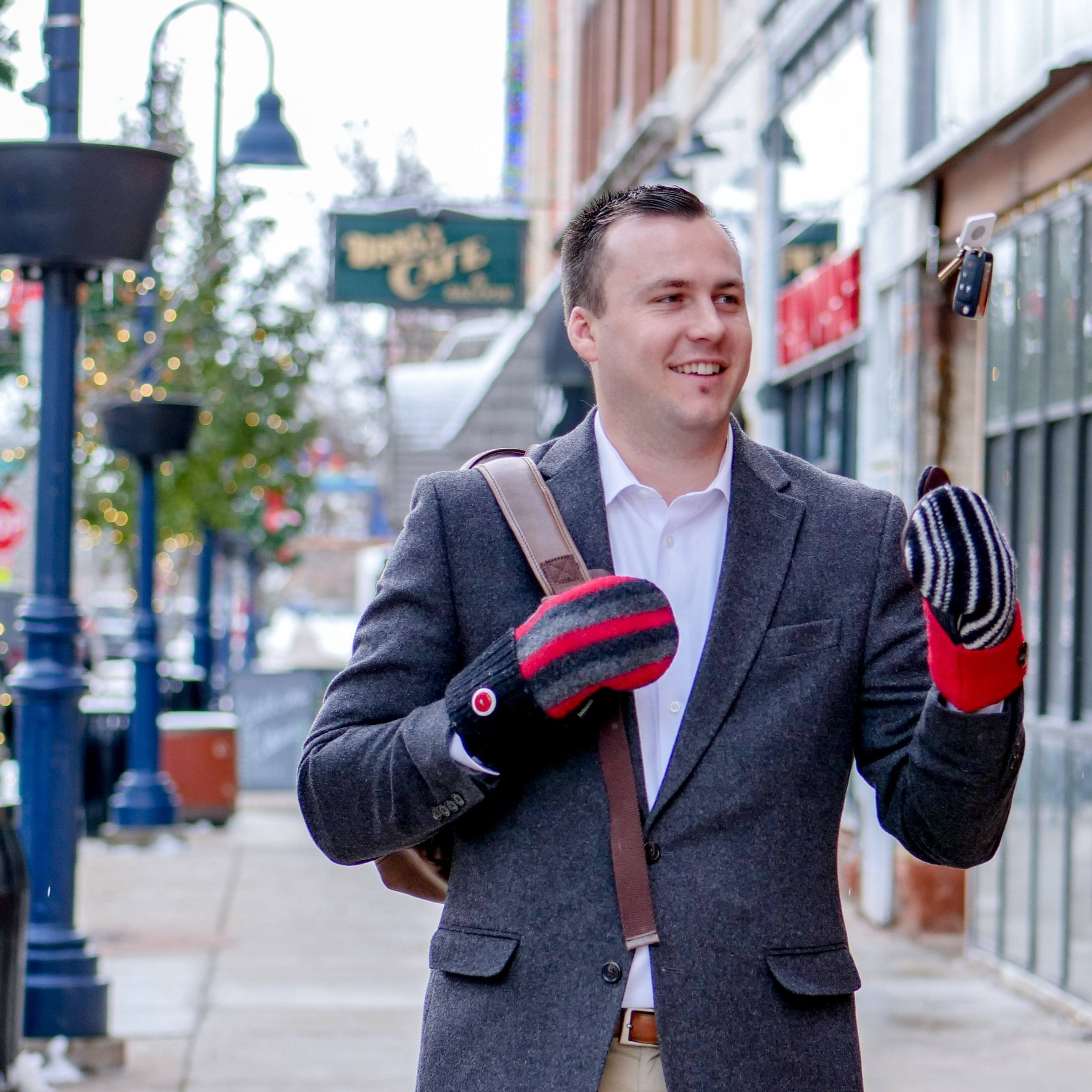 man wearing red black and gray wool sweater mittens and tossing keys in air